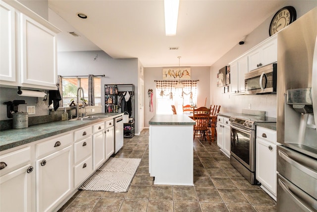 kitchen featuring appliances with stainless steel finishes, a wealth of natural light, a sink, and a kitchen island