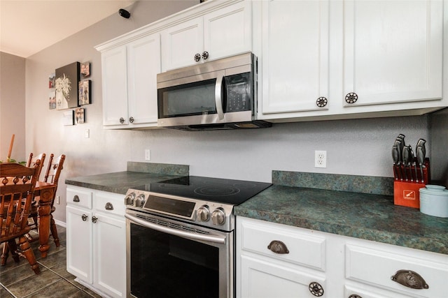 kitchen with stainless steel appliances, dark countertops, and white cabinetry