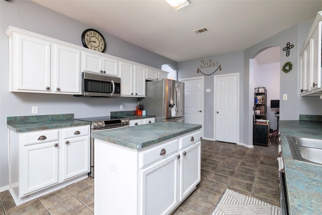 kitchen featuring arched walkways, visible vents, white cabinets, appliances with stainless steel finishes, and dark countertops