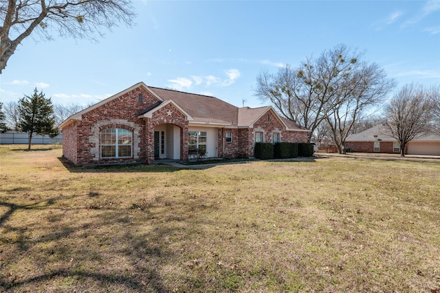 view of front of house with brick siding, fence, and a front lawn