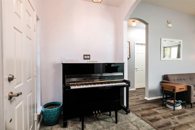 living area with dark wood-type flooring, arched walkways, and baseboards