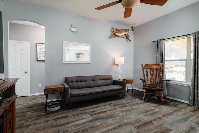 sitting room with arched walkways, wood finished floors, a ceiling fan, and baseboards