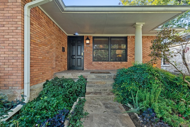 doorway to property with covered porch and brick siding