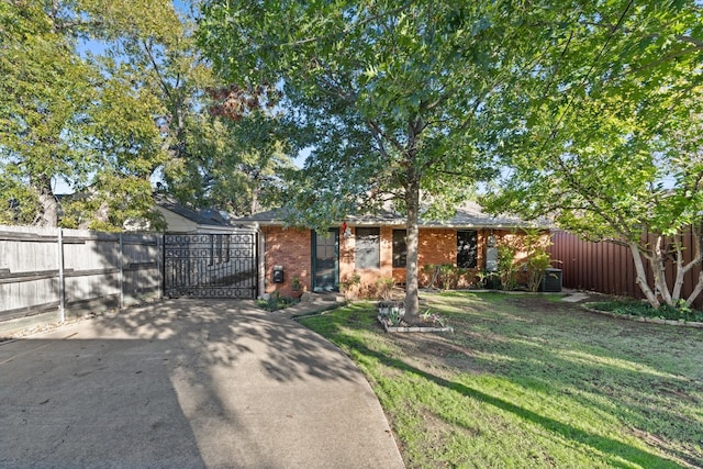 view of front facade featuring brick siding, a gate, fence, and a front yard