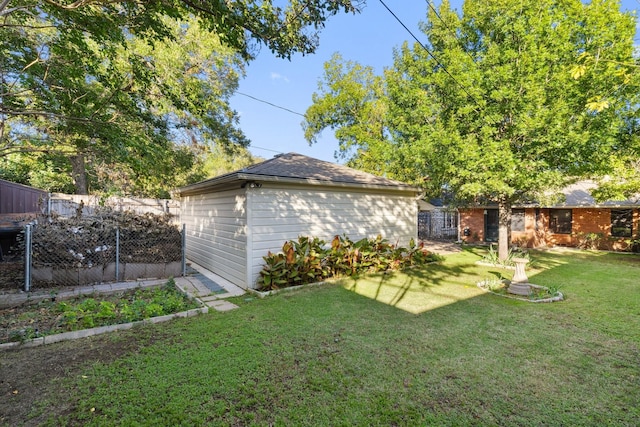 view of yard with an outdoor structure, fence, and a garden