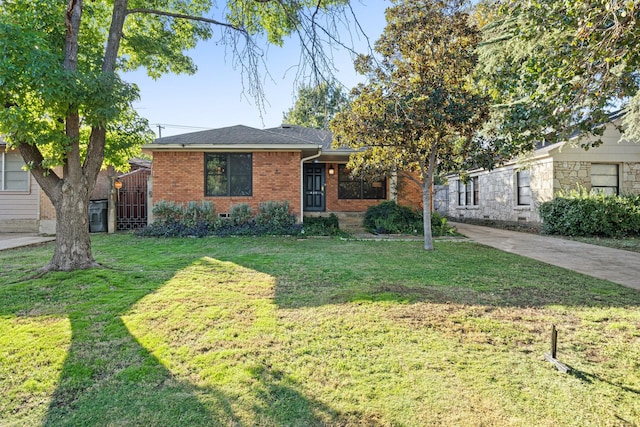 view of front of home featuring brick siding, a front lawn, and a shingled roof