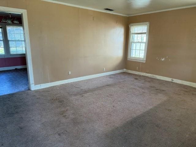 carpeted spare room with ornamental molding, visible vents, and baseboards