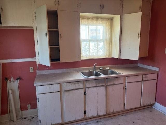 kitchen with light countertops, a sink, and baseboards