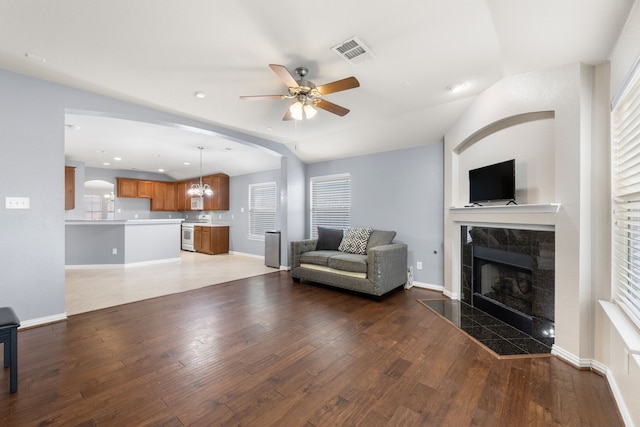 unfurnished living room featuring a fireplace, visible vents, hardwood / wood-style floors, baseboards, and ceiling fan with notable chandelier