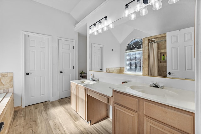 bathroom featuring lofted ceiling, wood finished floors, a shower with shower curtain, and a sink