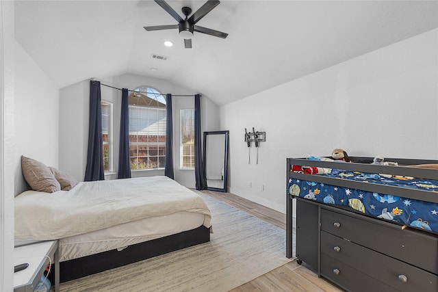 bedroom featuring light wood-style floors, ceiling fan, visible vents, and vaulted ceiling