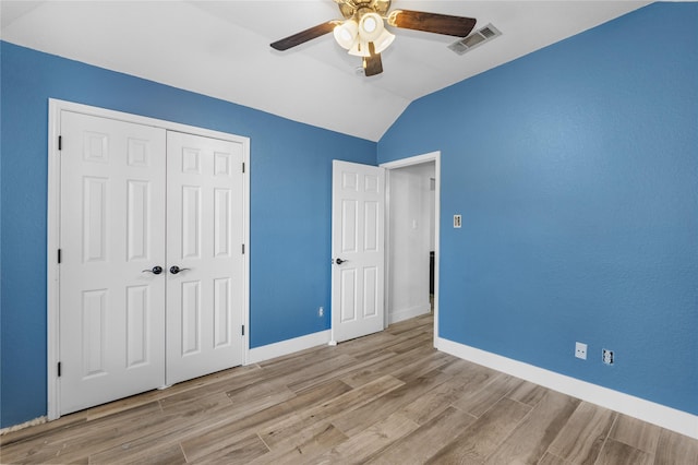 unfurnished bedroom with wood finished floors, visible vents, baseboards, vaulted ceiling, and a closet