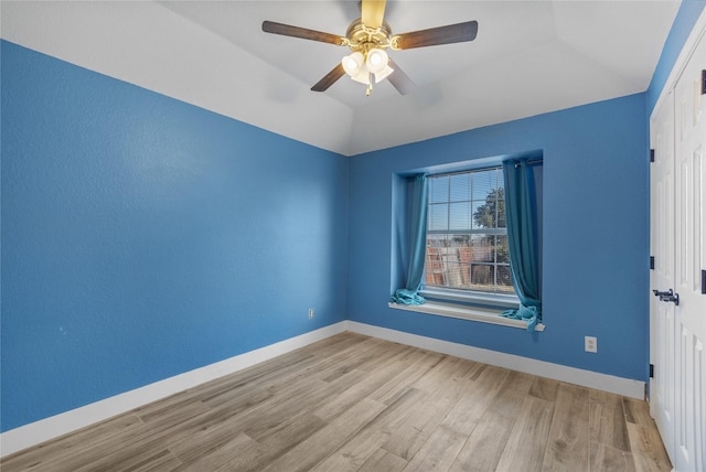 unfurnished room featuring a ceiling fan, baseboards, vaulted ceiling, and wood finished floors