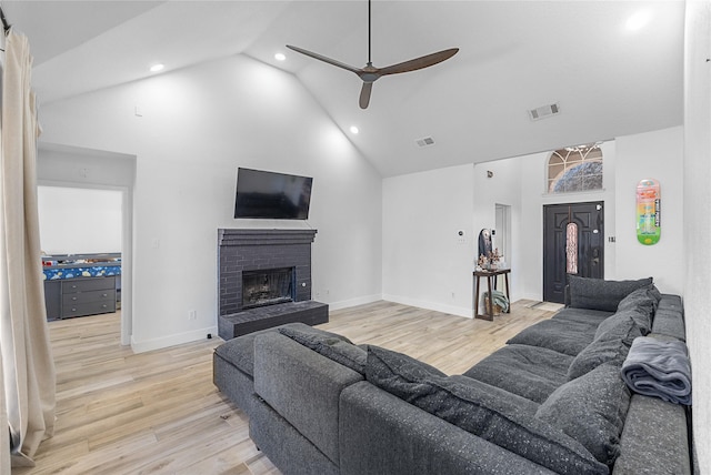 living area with a fireplace, light wood finished floors, visible vents, a ceiling fan, and high vaulted ceiling