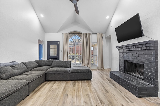 living area featuring a fireplace, lofted ceiling, recessed lighting, ceiling fan, and light wood-type flooring