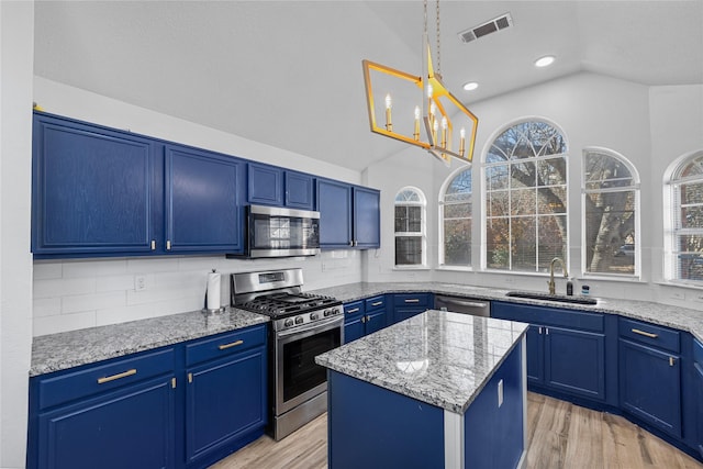 kitchen with stainless steel appliances, visible vents, vaulted ceiling, a sink, and blue cabinets