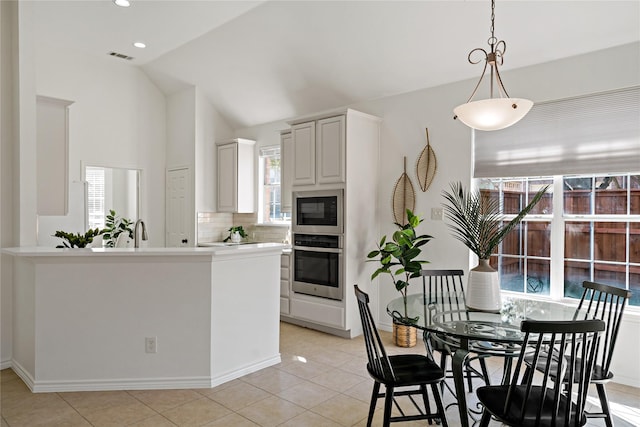 kitchen with built in microwave, vaulted ceiling, stainless steel oven, pendant lighting, and backsplash