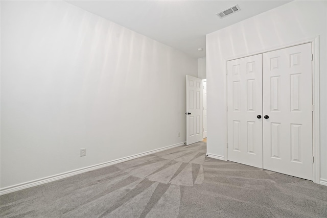 unfurnished bedroom with carpet, a closet, visible vents, and baseboards