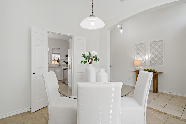 dining space featuring arched walkways, light tile patterned flooring, and baseboards