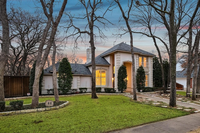 view of front facade featuring a yard, fence, and stucco siding