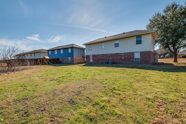 rear view of house with a yard, fence, a playground, and brick siding