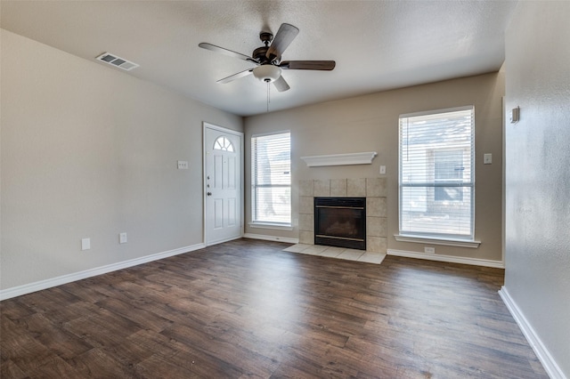 unfurnished living room with visible vents, plenty of natural light, baseboards, and wood finished floors