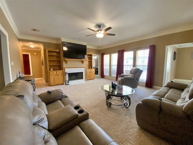 living area featuring crown molding, baseboards, a tiled fireplace, light carpet, and a ceiling fan