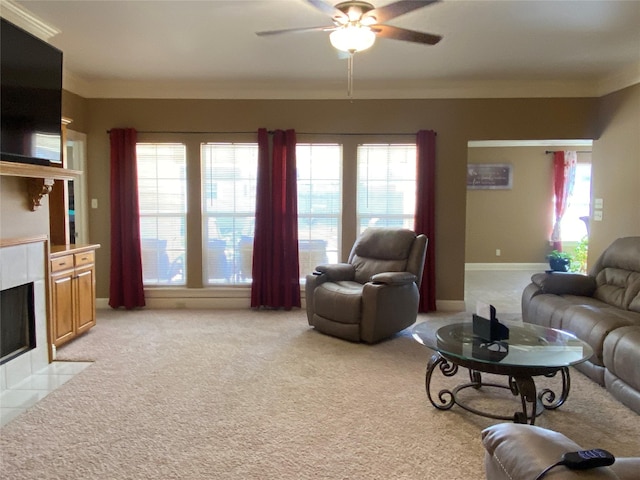 living area with baseboards, ceiling fan, light carpet, a tiled fireplace, and crown molding