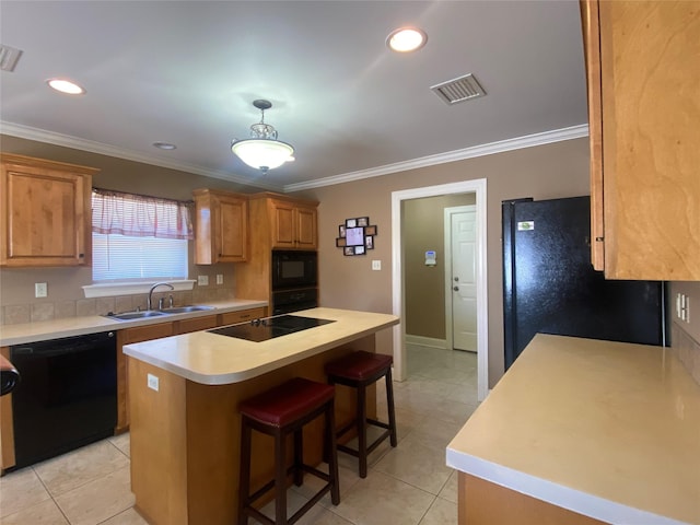 kitchen featuring visible vents, a kitchen island, a breakfast bar, black appliances, and a sink