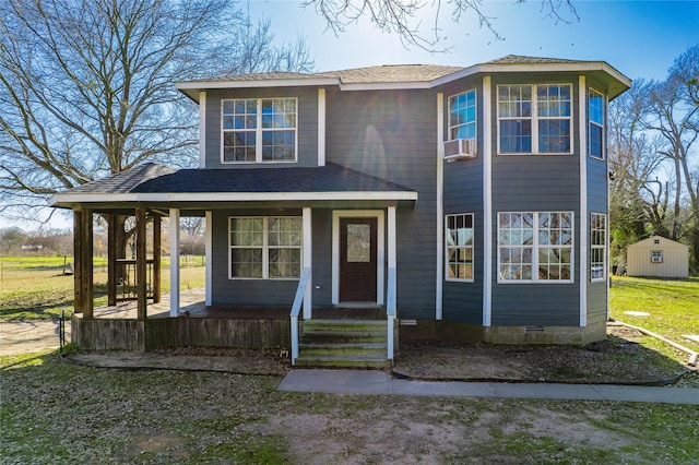 view of front facade with covered porch, a shingled roof, crawl space, and an outbuilding