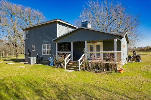 view of front of home with covered porch, a front lawn, a chimney, and central AC unit