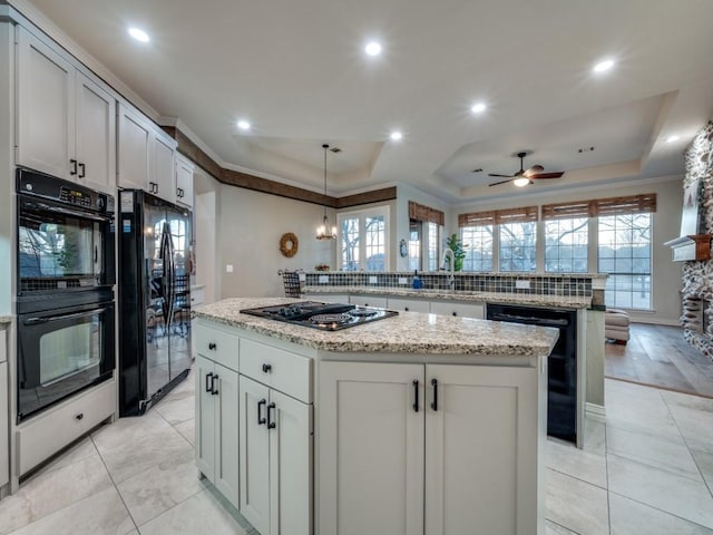 kitchen featuring a center island, a tray ceiling, black appliances, and recessed lighting