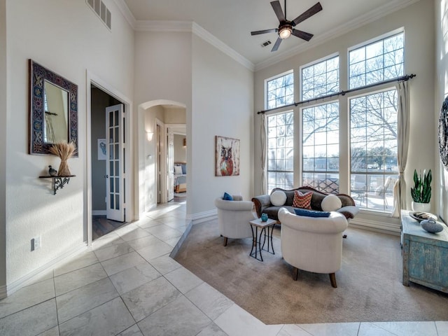 living room with ornamental molding, arched walkways, a wealth of natural light, and a towering ceiling