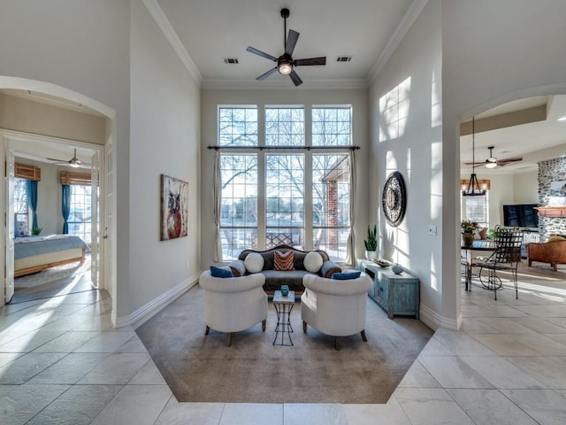 living room featuring arched walkways, ornamental molding, a towering ceiling, and visible vents