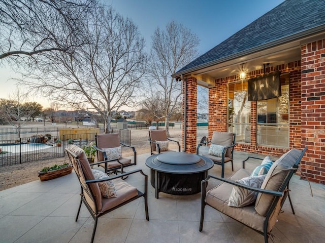 patio terrace at dusk featuring fence and a fire pit