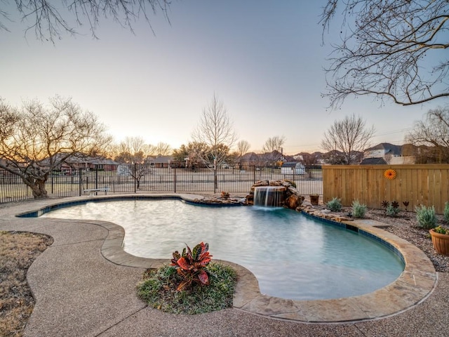 pool at dusk with a fenced backyard and a fenced in pool