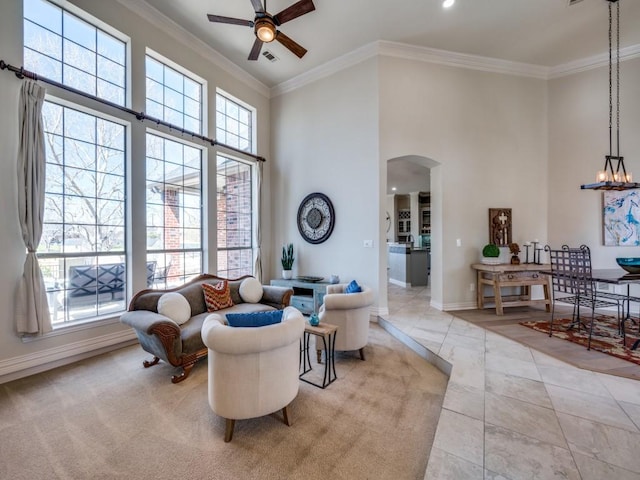 sitting room with a towering ceiling, baseboards, arched walkways, and ornamental molding