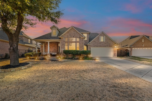 view of front of home with a garage, brick siding, driveway, and fence