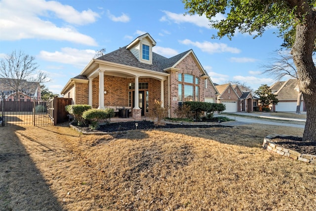 view of front of house with roof with shingles, a gate, fence, a porch, and brick siding