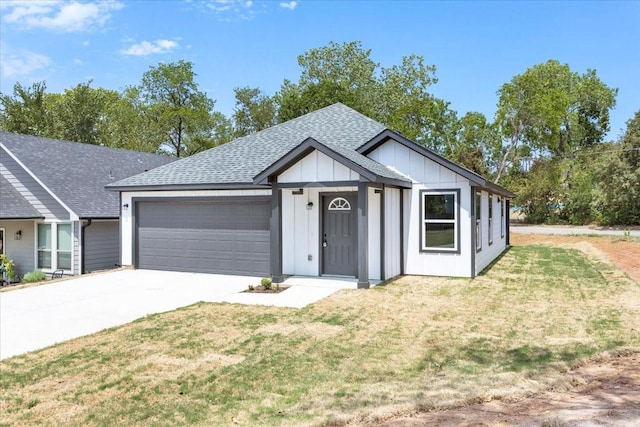 view of front of house featuring a garage, driveway, a shingled roof, board and batten siding, and a front yard