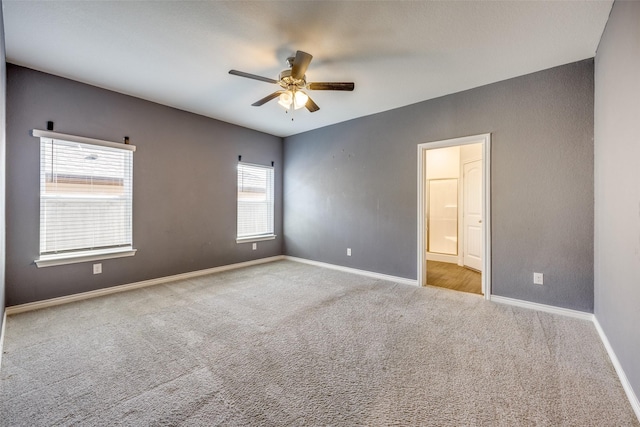 carpeted empty room with a ceiling fan and baseboards