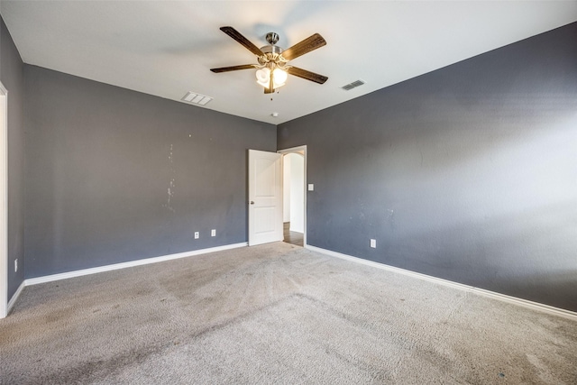 carpeted spare room with baseboards, visible vents, and a ceiling fan