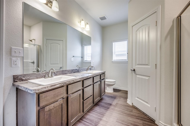 full bathroom featuring a shower, wood finished floors, a sink, and visible vents