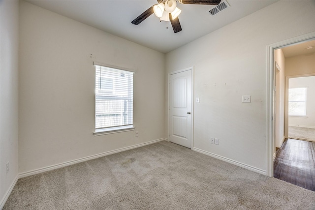 empty room with carpet floors, visible vents, baseboards, and a ceiling fan