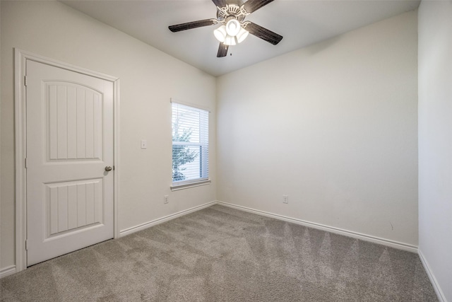 carpeted spare room featuring baseboards and a ceiling fan