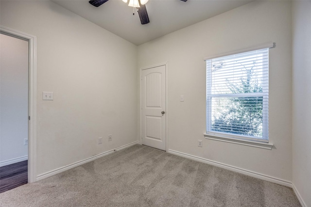 carpeted spare room featuring a ceiling fan and baseboards