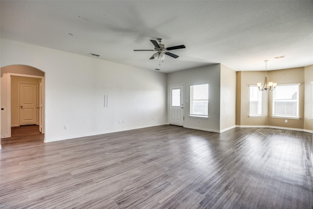 spare room with plenty of natural light, arched walkways, wood finished floors, and ceiling fan with notable chandelier