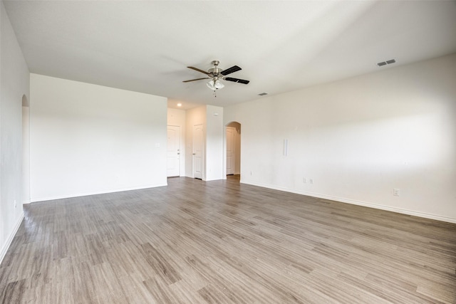 unfurnished room with a ceiling fan, arched walkways, visible vents, and light wood finished floors