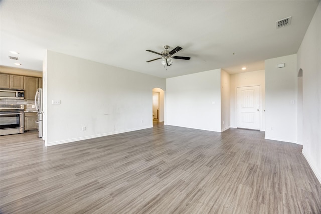 unfurnished living room with arched walkways, visible vents, ceiling fan, and light wood finished floors