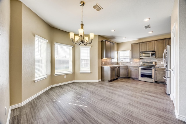 kitchen featuring light wood-style floors, tasteful backsplash, visible vents, and stainless steel appliances